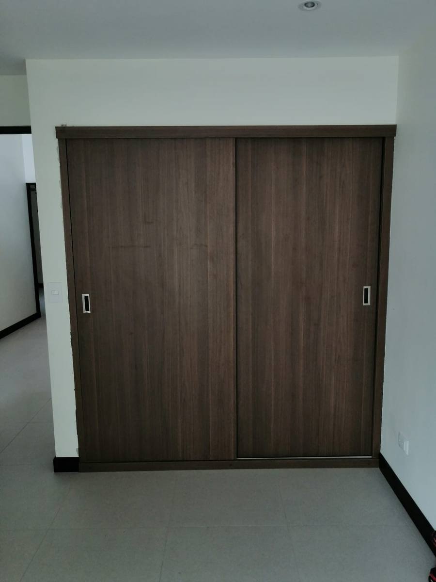 Closet con puertas corredizas en acabado nogal oscuro